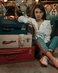 A woman sits beside three suitcases for an article on Culture for Houghton & Mackay Magazine