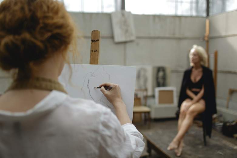 A lady sits in a pose whilst an artist sketches her outline for an article on Art by Houghton & Mackay