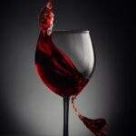 A glass of red wine swishes across the page for an article on Red Wine for Houghton & Mackay