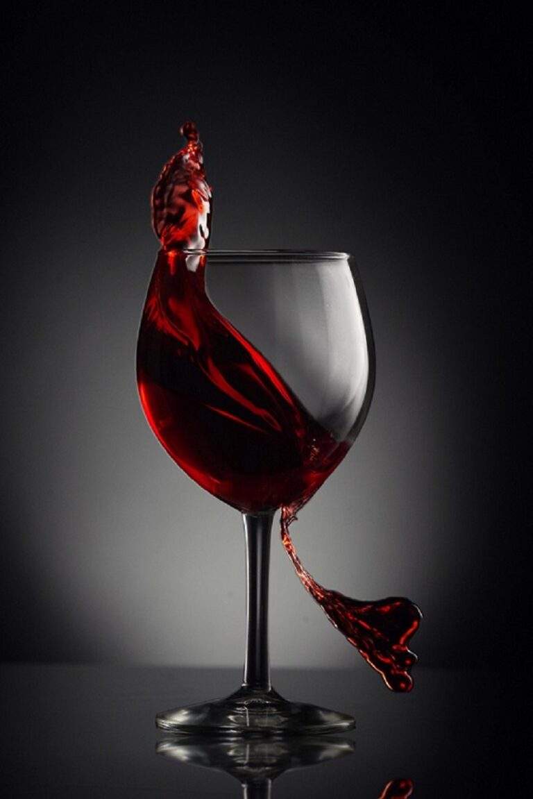 A glass of red wine swishes across the page for an article on Red Wine for Houghton & Mackay