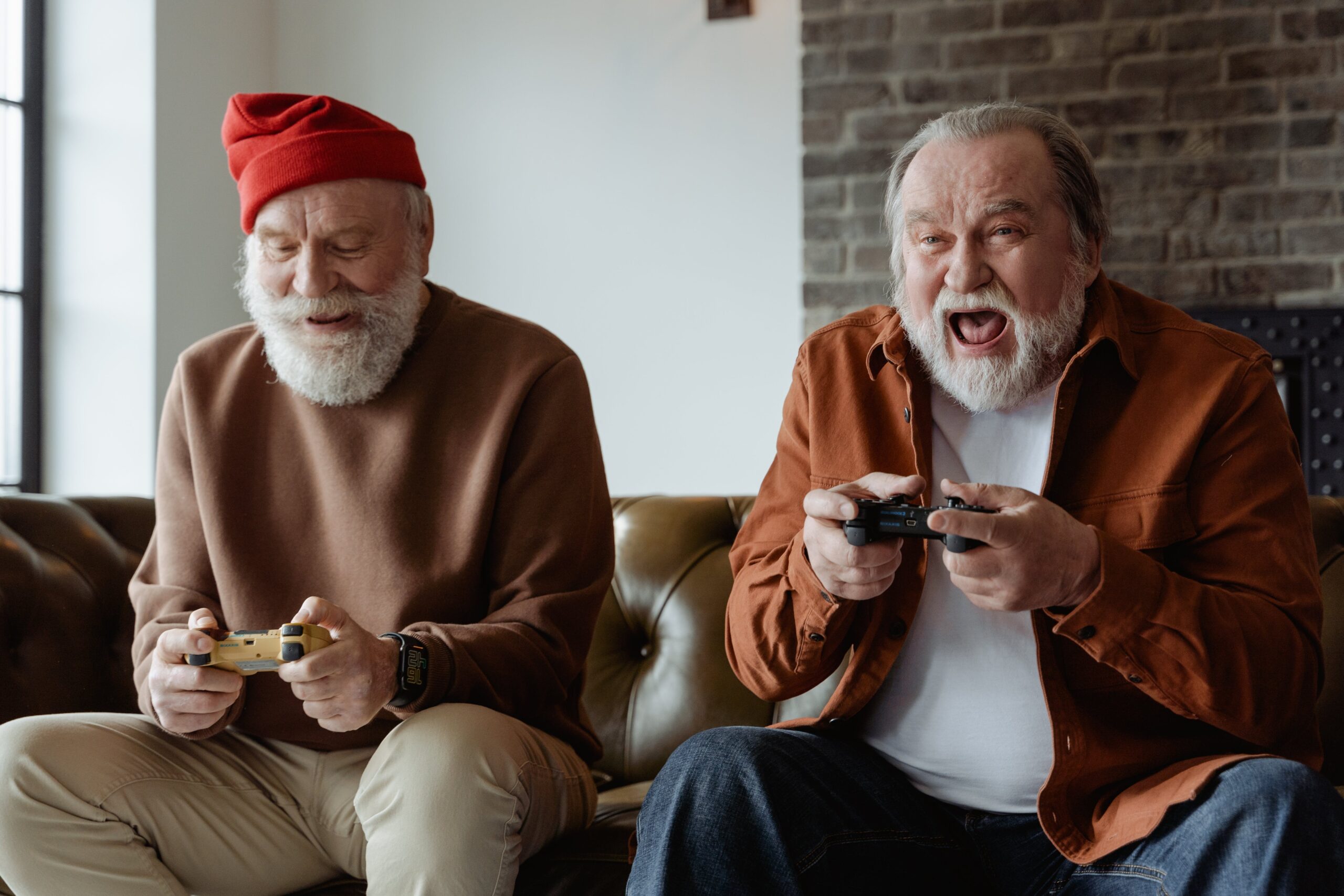 Two retired old men play video games whilst laughing