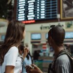 Two ladies at an airport board awaiting their ride