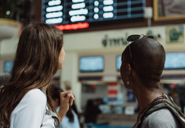 Two ladies at an airport board awaiting their ride