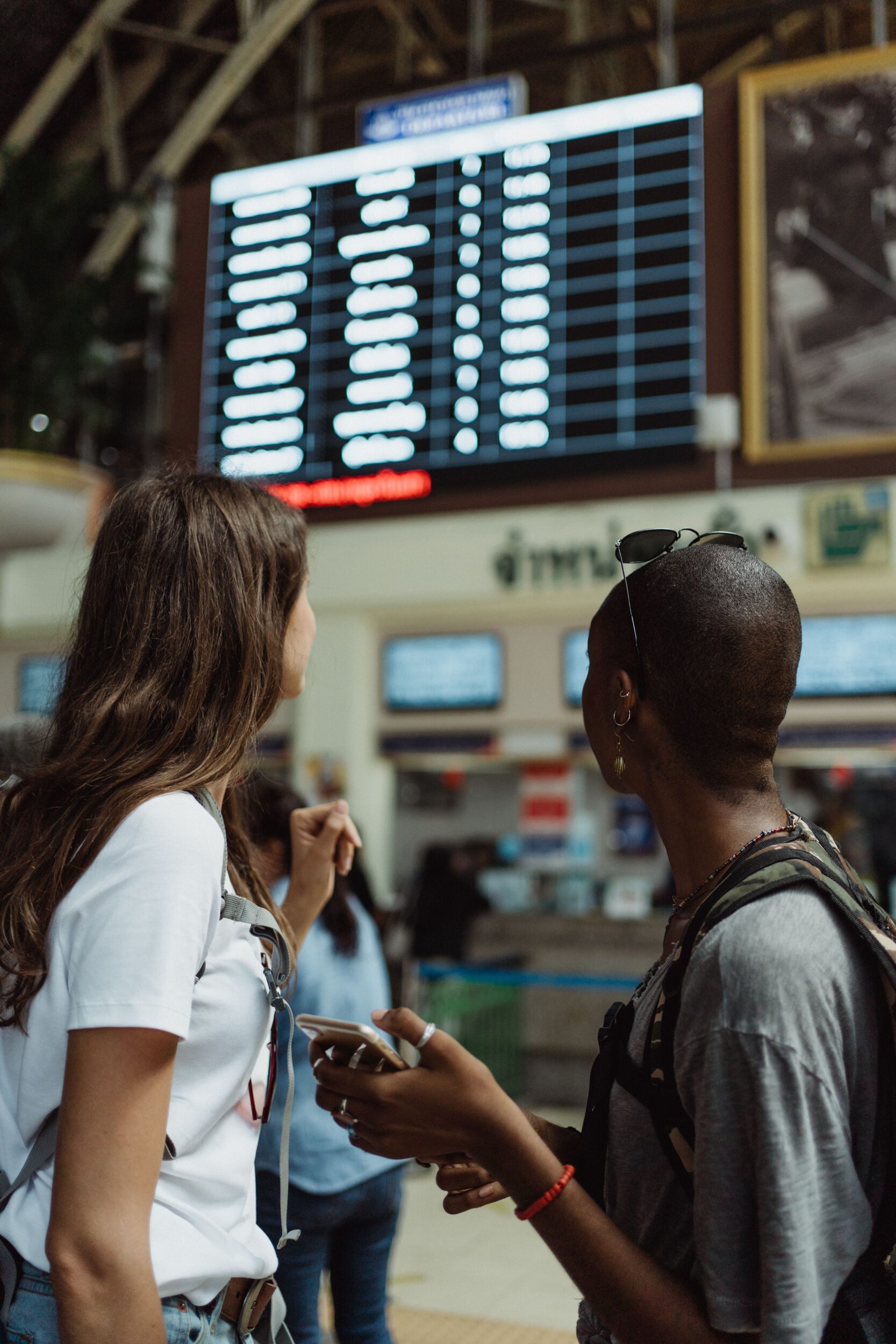 Two ladies at an airport board awaiting their ride