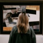 A woman stands in front of some art in a gallery, it is abstract.